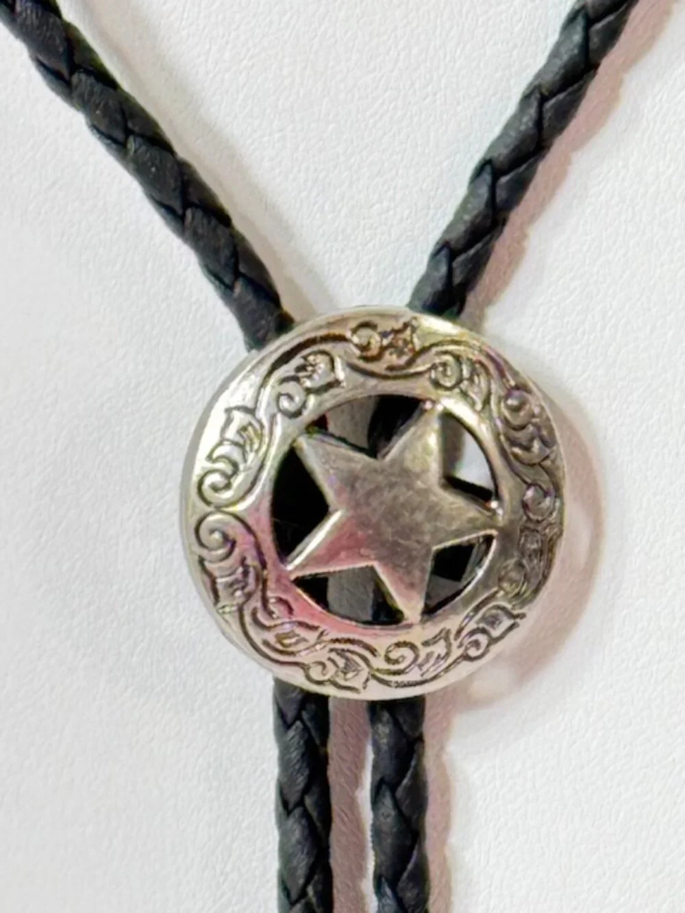 Silver-tone sheriff star and black cord western cowboy bolo tie.